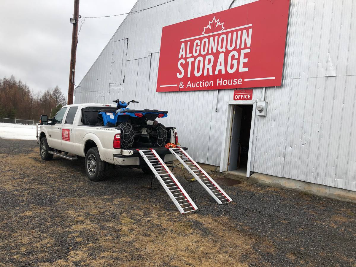 The Algonquin Storage office and sign on Ena Ave, with a pickup unloading an ATV