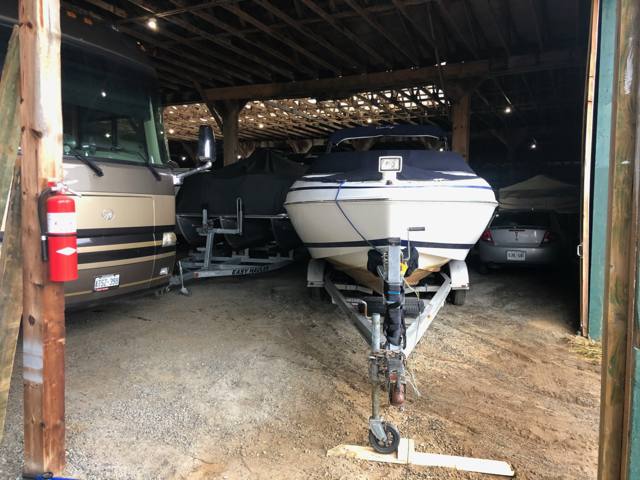 A motorhome and a boat under the covered barn roof
